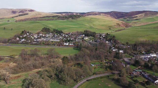 A peaceful Scottish village of Eddleston nestled among lush green fields and rolling hills in the rural Borders countryside