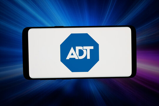 Stuttgart, Germany - 04-10-2026: In this photo illustration, the logo of US security company ADT Inc. is displayed on a smartphone in front of abstract background on computer screen.