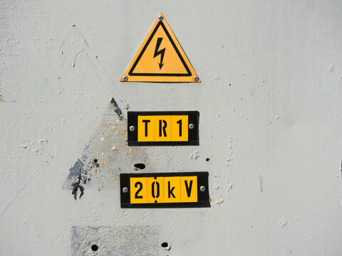 High Voltage Warning Sign with Lightning Bolt and 20kV Transformer Label on Weathered Grey Wall at Electrical Substation | Power, Danger and Energy Infrastructure