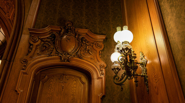 Ornate wooden doorway with antique wall sconce and textured wallpaper
