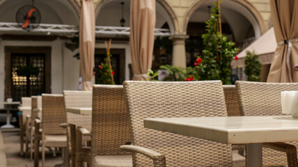 Fototapeta premium Outdoor cafe seating with wicker chairs and tables under arches
