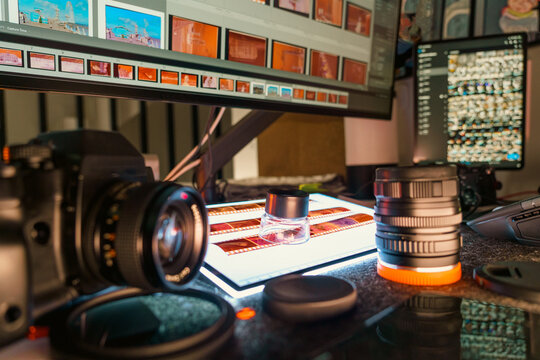 Photographer hand using magnifying loupe inspecting film strips