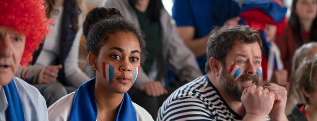 Obraz premium Worried football fans supproting French national team in live soccer match at stadium.