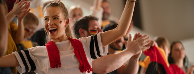 Football fans supproting German national team in live soccer match at stadium. © Halfpoint