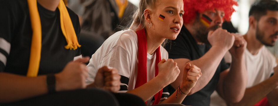 Worried football fans supproting German national team in live soccer match at stadium.