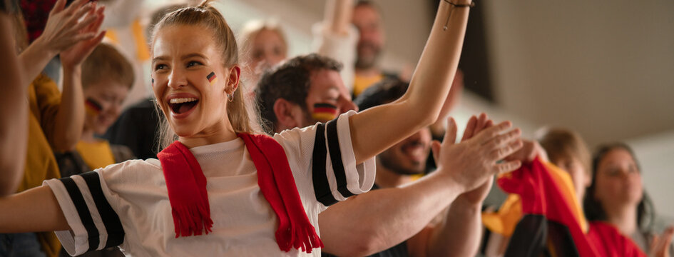 Football fans supproting German national team in live soccer match at stadium.