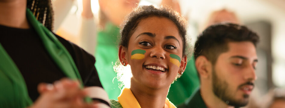 Brazilian young sisters football fans supporting their team at stadium.
