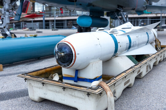 Cold War smart bomb with optical guidance sensor on airbase, vintage weapon highlighting global arms trade concept