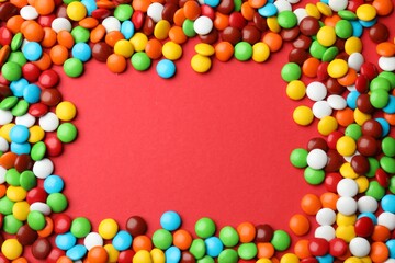 Obraz premium Frame made of delicious colorful candies on red background, top view. Space for text