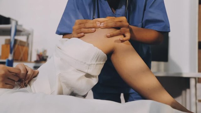 Doctor examining leg of female patient in examination room