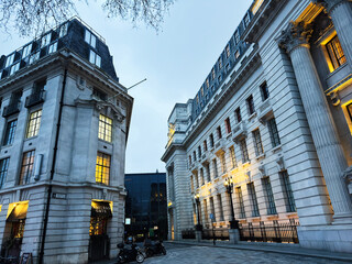 Naklejka premium Evening city Muscovy street in London UK with historic neoclassical architecture, Traitors Gate illuminated facades and columns at blue hour