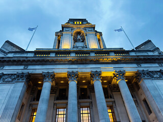 Naklejka premium Historic neoclassical civic building with grand columns and illuminated facade in London, UK at dusk. Four Seasons Hotel London at Ten Trinity Square.