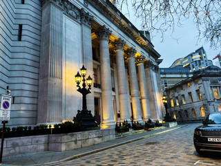 Naklejka premium Grand neoclassical Four Seasons Hotel London at Ten Trinity Square building with illuminated Corinthian columns and ornate lamp posts in London, UK evening cityscape
