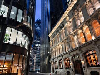 Naklejka premium Evening business architecture in the City of London UK with illuminated historic facade and modern glass towers creating a dramatic urban skyline