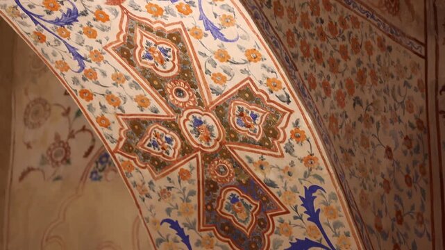 Slow pan inside an ancient church revealing an ornate interior. The walls and vaulted ceilings are beautifully adorned with vibrant religious frescoes, intricate murals, and elaborate decorative patte