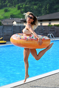 Happy cheerful woman jumping near the swimming pool