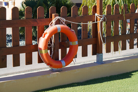 safety in summer. lifeguard float placed on the wooden fence of a swimming pool