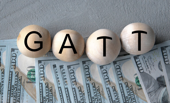 GATT - word on wooden balls on the background of banknotes