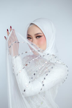 Elegant woman wears a white hijab and embellished veil