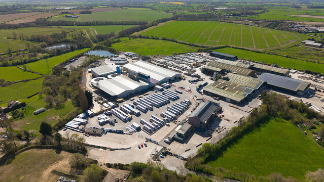 Aerial view of a concrete product supplier facility with industrial warehouses and storage yards surrounded by green fields in Ellistown, England, United Kingdom.