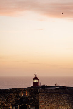 Lighthouse atop old stone fort at sunset in warm photographic style on calm ocean background, concept of coastal serenity