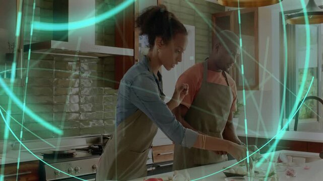 Woman passing ingredient to man, cooking and chopping at counter, teal overlay sweeping over them