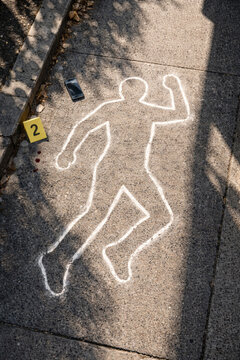 Chalk outline of a body on pavement with phone nearby