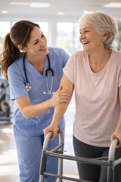 Caring nurse assisting senior woman with mobility in recovery ce