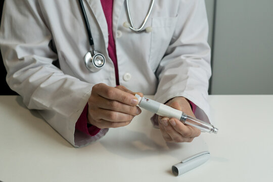 A doctor in a white lab coat showing how to adjust and prepare an insulin injection pen for diabetes treatment.