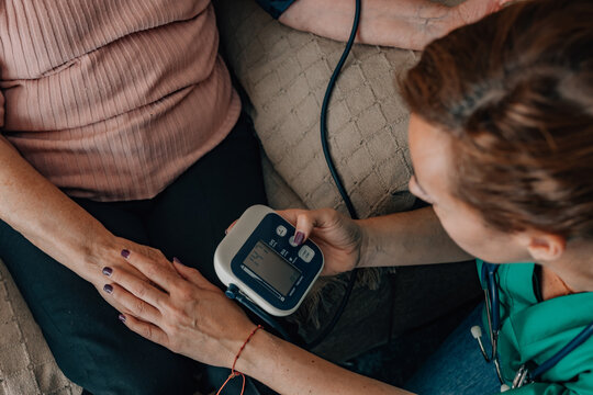 Home Healthcare -healthcare professional uses a digital wrist monitor to check an elderly patient's blood pressure during a compassionate home visit, emphasizing accessible, personalized care