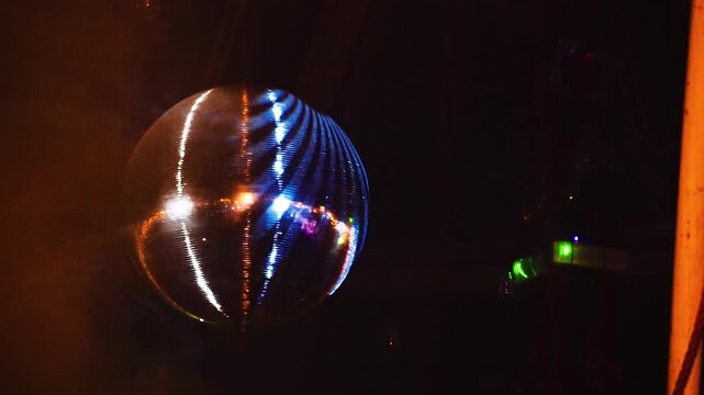 Discokugel mit orangefarbenem Licht und Nebelmaschine im Club Party und Festival Atmosph&auml;re bei Nacht