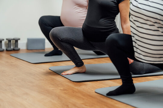 Group doing prenatal stretching in realistic style on indoor studio floor, concept of wellness and healthy lifestyle