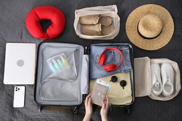 Woman packing suitcase for trip on bed, top view