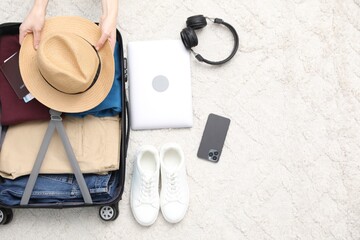 Naklejka premium Woman packing suitcase for trip indoors, top view
