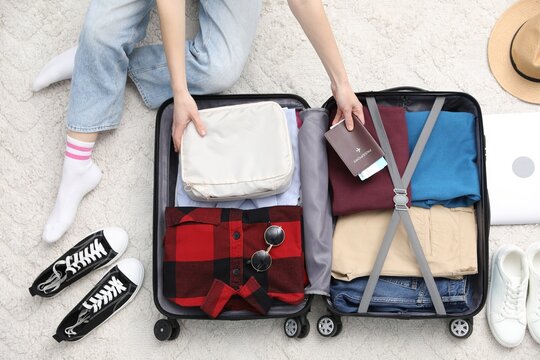 Woman packing suitcase for trip indoors, top view