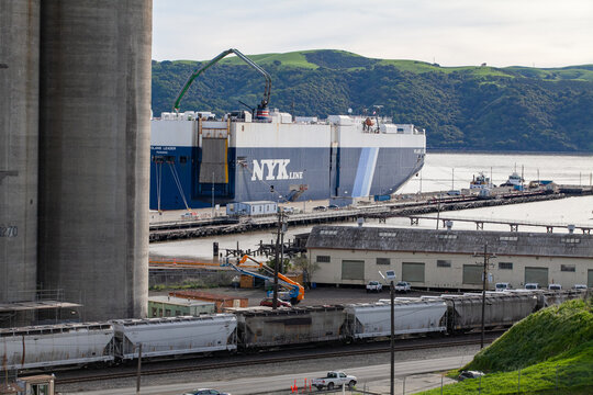 Industrial waterfront silos and cargo vessel operations along the Martinez shoreline