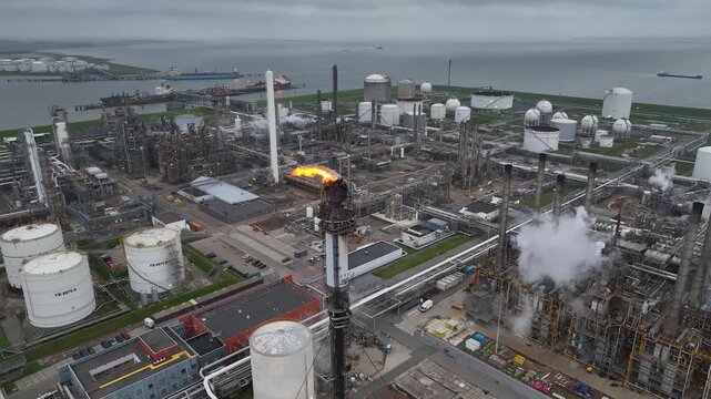 Aerial view of a chemical plant at sunset. Drone shot. Curling fire and cumin smoke filling the sky. Smoking chimneys from the factory. Chimneys of an oil refinery at sunrise pollute the environment