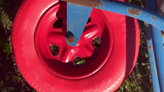 Close up of a red wheelbarrow wheel on grass. Gardening, tools.