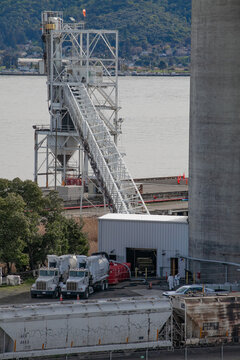 Industrial loading facility with conveyor system and two workers operating along the Martinez waterfront