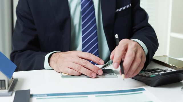 
Businessman shields tiny house with hand. Office desk holds coffee cup and pens. Professional demeanor suggests protection or security. Ideal for insurance, real estate, or financial services