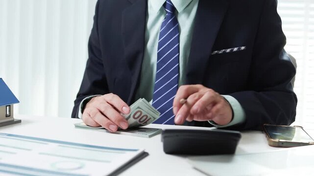 
Businessman shields tiny house with hand. Office desk holds coffee cup and pens. Professional demeanor suggests protection or security. Ideal for insurance, real estate, or financial services