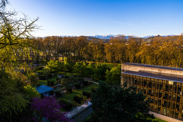 Fototapeta premium Hôtel du Département and its gardens in Pau seen from the Boulevard des Pyrénées with the snow-capped Pyrenees chain in the background in spring