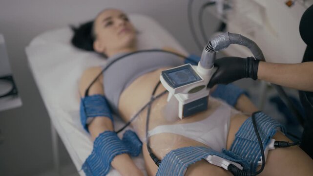 A young woman receives a non-invasive cryolipolysis treatment to reduce unwanted fat. This modern beauty procedure targets stubborn areas for body contouring.