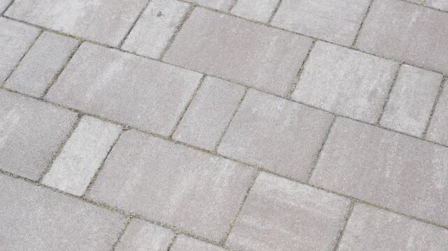 Close-up of light gray paving stones arranged in geometric pattern. Clean surface texture for urban walkway background.