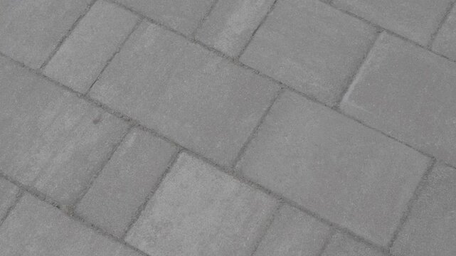 Light gray paving stones filmed from above in soft motion. Clean geometric pavement texture for urban background use.