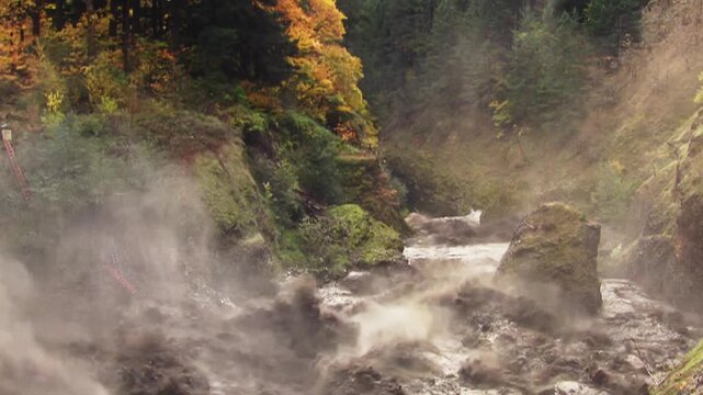 Destructive mudflow surging through a scenic canyon during a fall flood event