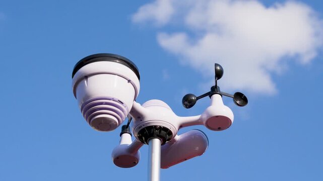 Weather station with wind cups and sensors installed on pole under clear sky. Urban meteorological observation equipment.