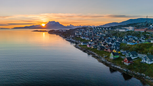 Aerial view of colorful houses along the rocky coastline at sunset with mountains in the distance Nuuk, Sermersooq Municipality, Greenland.