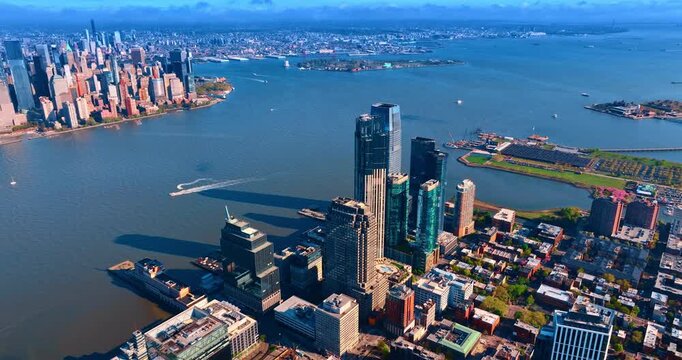 Picturesque urban landscape at the river waterfront. Few boats are moving by the waterscape. Manhattan across the river from Jersey City side. Aerial view.
