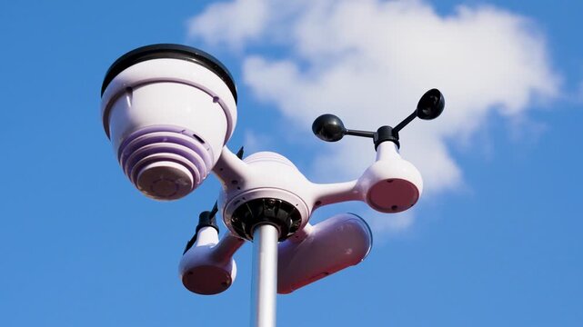 Decorative street lamp with weather sensor instruments against bright blue sky and cloud. Minimal urban infrastructure scene.